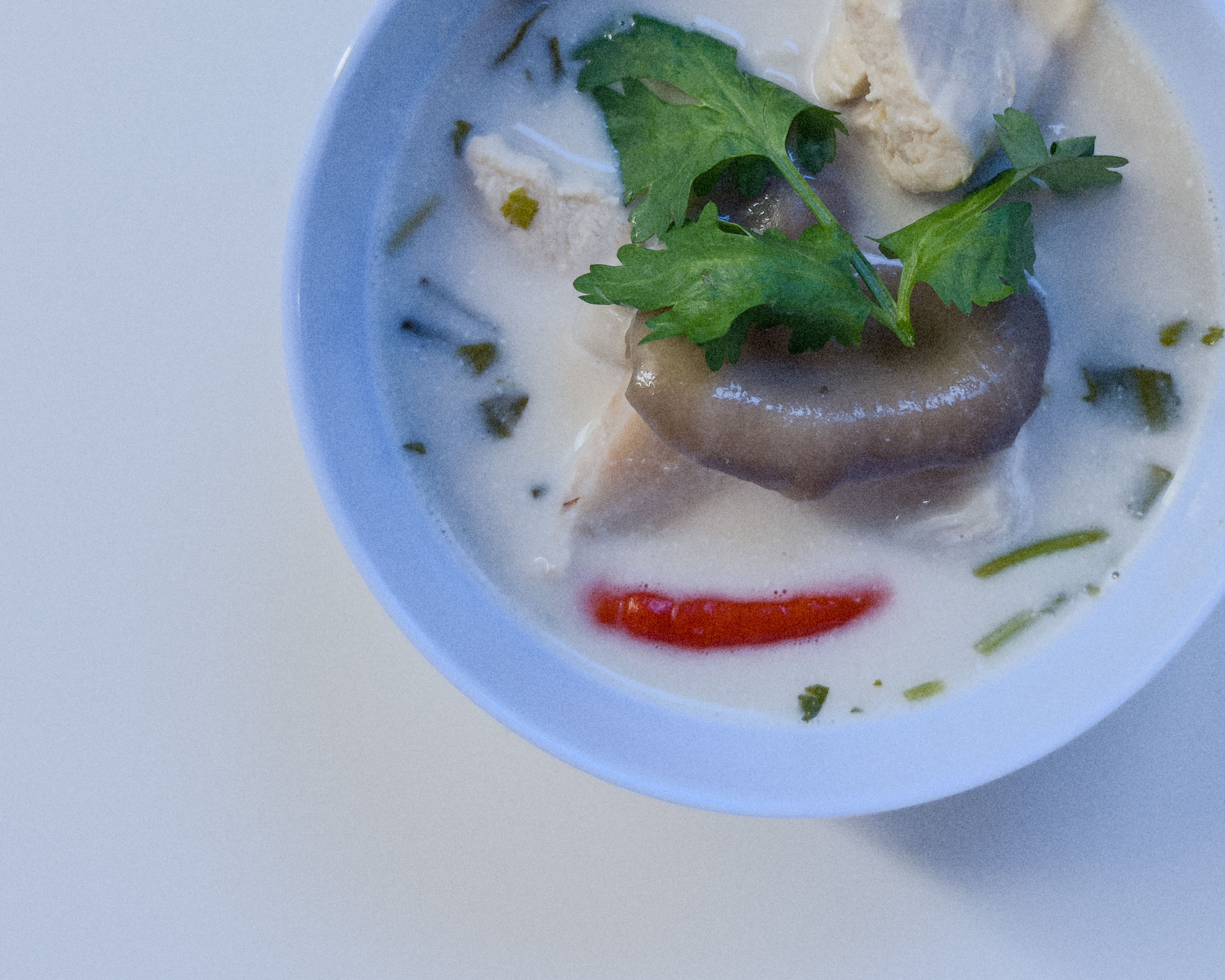 Authentische Tom Kha Gai - cremige thailändische Kokos-Hühnersuppe mit Galgant, Zitronengras, Pilzen und Chili.